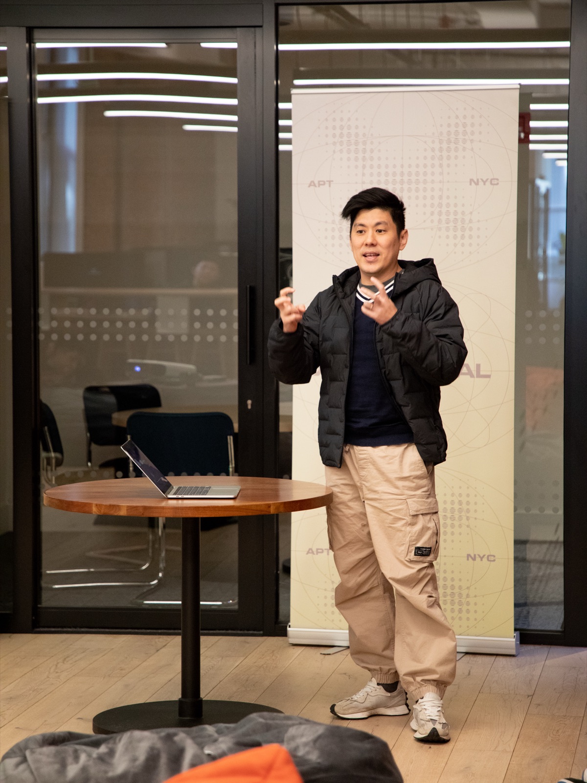 Vin Lim presenting his project at Aptos Xponential in New York, standing beside a laptop in front of the Aptos NYC banner