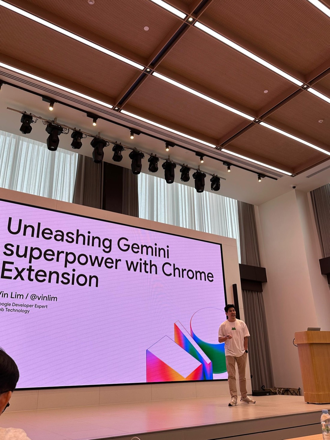 Vin Lim on stage at Google I/O Extended Bangkok 2025 in front of a large screen showing the title slide, Unleashing Gemini superpower with Chrome Extension