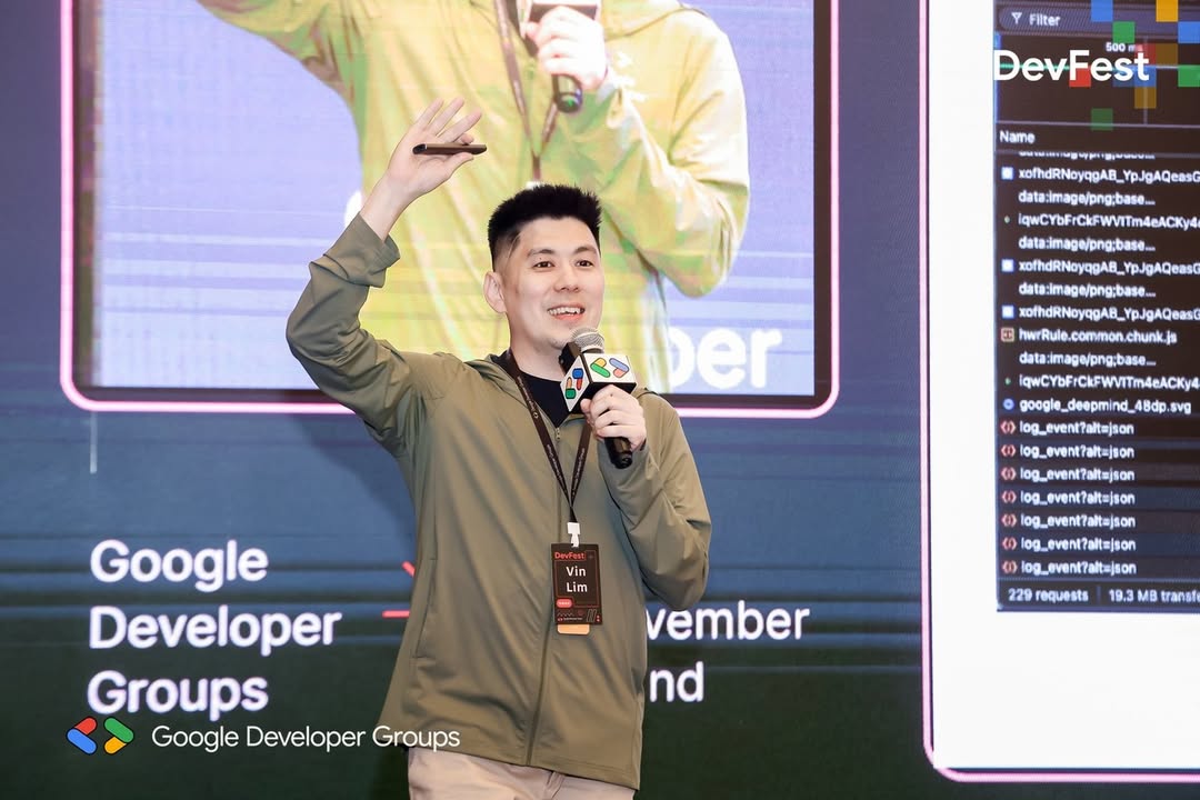 Vin Lim waving to the audience with a microphone at 2025 Google DevFest Shanghai, with the DevTools Network panel on the screen behind him